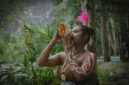 Seorang belian dari Suku Dayak Benuaq dengan pakaian adat lengkap sedang melakukan ritual penyembuhan, memperlihatkan kekayaan budaya dan spiritualitas yang mendalam di pedalaman Kalimantan. Gerakan tubuh dan ekspresi wajahnya memancarkan energi yang kuat, menjadi pusat perhatian dalam upacara adat yang penuh makna.