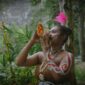 Seorang belian dari Suku Dayak Benuaq dengan pakaian adat lengkap sedang melakukan ritual penyembuhan, memperlihatkan kekayaan budaya dan spiritualitas yang mendalam di pedalaman Kalimantan. Gerakan tubuh dan ekspresi wajahnya memancarkan energi yang kuat, menjadi pusat perhatian dalam upacara adat yang penuh makna.