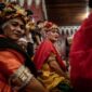 Seorang balian atau dukun adat Dayak Benuaq sedang melakukan ritual Belian, menari dalam kondisi trans diiringi musik tradisional, memohon kesembuhan dan keseimbangan alam. Pakaian adat dan ornamen khas menambah kesan sakral pada upacara yang sarat makna spiritual ini.