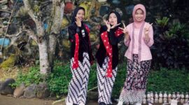 Seorang model berpose anggun mengenakan busana batik Kalimantan Timur dengan motif kontemporer, menunjukkan bagaimana warisan budaya dapat diinterpretasikan ulang menjadi tren mode yang relevan. Perpaduan warna cerah dan desain modern ini berhasil menarik perhatian pasar fashion global, membuktikan fleksibilitas batik dalam berbagai gaya.