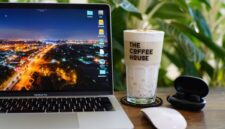 Seorang individu menikmati kopi di kafe modern yang dipenuhi tanaman hijau, mencerminkan perpaduan antara produktivitas dan ketenangan dalam gaya hidup urban masa kini. Suasana yang nyaman mendukung fokus sekaligus relaksasi di tengah kesibukan kota.