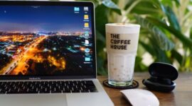 Seorang individu menikmati kopi di kafe modern yang dipenuhi tanaman hijau, mencerminkan perpaduan antara produktivitas dan ketenangan dalam gaya hidup urban masa kini. Suasana yang nyaman mendukung fokus sekaligus relaksasi di tengah kesibukan kota.