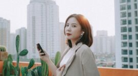 Seorang profesional muda melakukan meditasi di atap gedung perkantoran saat matahari terbenam, merefleksikan upaya mencari ketenangan di tengah padatnya kehidupan kota besar. Momen ini menunjukkan pentingnya menemukan jeda dari kesibukan untuk menjaga kesehatan mental di lingkungan perkotaan yang serba cepat.