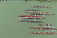 Pemandangan matahari terbenam di Sungai Mahakam, menampilkan perahu tradisional yang berlayar tenang di atas air, mencerminkan kehidupan damai masyarakat lokal yang bergantung pada sungai ini. Latar belakang hutan lebat di tepian sungai menunjukkan kekayaan alam Kalimantan Timur yang perlu terus dijaga.