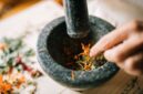Seorang ahli pengobatan tradisional di Kutai sedang menyiapkan ramuan herbal dari berbagai jenis akar dan dedaunan khas Kalimantan, menunjukkan kekayaan kearifan lokal dalam meracik obat alami. Proses peracikan ini menjadi bagian tak terpisahkan dari budaya masyarakat Kutai dalam menjaga kesehatan tubuh secara turun-temurun.