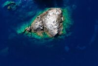 Pemandangan udara Kepulauan Derawan memperlihatkan gradasi warna biru laut yang menawan, dikelilingi oleh terumbu karang sehat dan pasir putih bersih, sebuah panorama surga bahari. Keindahan ini merupakan magnet utama bagi wisatawan yang mencari pengalaman menyelam dan bersnorkeling kelas dunia.