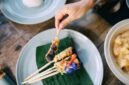 Hidangan sanga yang baru diangkat dari bara api, memperlihatkan bungkusan daun pisang layu dengan aroma harum yang menggoda selera. Nasi bakar khas Minang ini siap untuk dinikmati dengan berbagai lauk pendamping.