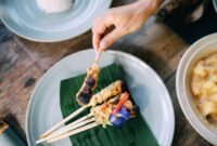 Hidangan sanga yang baru diangkat dari bara api, memperlihatkan bungkusan daun pisang layu dengan aroma harum yang menggoda selera. Nasi bakar khas Minang ini siap untuk dinikmati dengan berbagai lauk pendamping.
