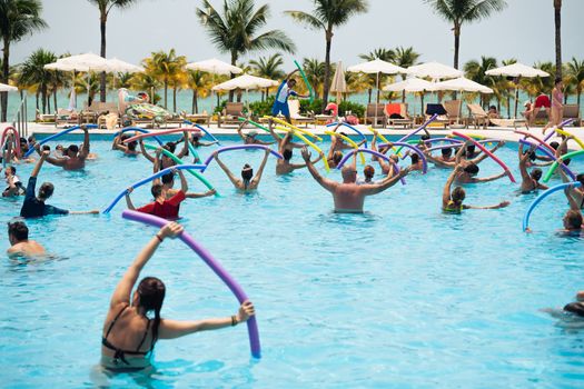 Sekelompok wanita lanjut usia tersenyum ceria saat melakukan gerakan aqua aerobik di dalam kolam renang, menunjukkan betapa olahraga air dapat dinikmati oleh semua kalangan usia. Air memberikan dukungan yang lembut sehingga latihan kebugaran terasa lebih ringan dan menyenangkan.