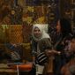 Seorang perajin batik dari Kalimantan Timur sedang dengan teliti menyelesaikan proses pewarnaan pada sehelai kain, menampilkan motif-motif khas flora dan fauna Borneo yang kaya akan detail dan makna.