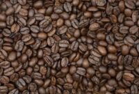 Seorang wanita tengah menyangrai biji kopi robusta yang telah dicampur parutan kelapa segar di atas bara api, sebuah proses penting dalam pembuatan kopi sanga tradisional khas Lombok. Pemandangan ini merefleksikan kearifan lokal dalam mengolah kekayaan alam menjadi minuman yang penuh cita rasa.