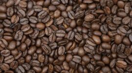 Seorang wanita tengah menyangrai biji kopi robusta yang telah dicampur parutan kelapa segar di atas bara api, sebuah proses penting dalam pembuatan kopi sanga tradisional khas Lombok. Pemandangan ini merefleksikan kearifan lokal dalam mengolah kekayaan alam menjadi minuman yang penuh cita rasa.