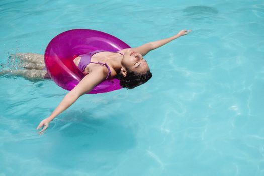 Seorang wanita sedang melakukan gerakan aqua-aerobik di kolam renang, menunjukkan bagaimana olahraga air dapat menjadi pilihan kebugaran yang menyenangkan dan menyegarkan. Gerakan di dalam air ini membantu memperkuat otot tanpa membebani sendi.