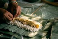 Sanga, nasi bakar khas Kalimantan yang dibungkus daun pisang dan dipanggang di atas bara api, menampilkan keunikan kuliner tradisional dengan aroma smoky yang memikat selera. Hidangan ini seringkali berisi ayam suwir atau ikan teri pedas.