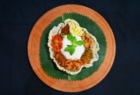 Sajian nasi kuning tumpeng lengkap dengan berbagai lauk pauk khas Indonesia, siap memeriahkan acara syukuran atau perayaan istimewa, menampilkan kekayaan warna dan rasa. Hidangan ini melambangkan kemakmuran dan keberuntungan, menjadi pusat perhatian dalam setiap kebersamaan yang penuh makna.