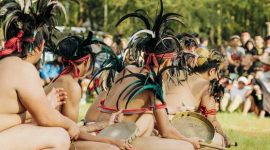 Seorang Balian, pemimpin ritual Belian dari suku Dayak Benuaq, mengenakan pakaian adat lengkap saat memimpin upacara sakral di tengah hutan Kalimantan. Kostumnya yang kaya detail dan penuh makna, dihiasi manik-manik serta bulu burung, melambangkan koneksi mendalam dengan alam dan roh leluhur.